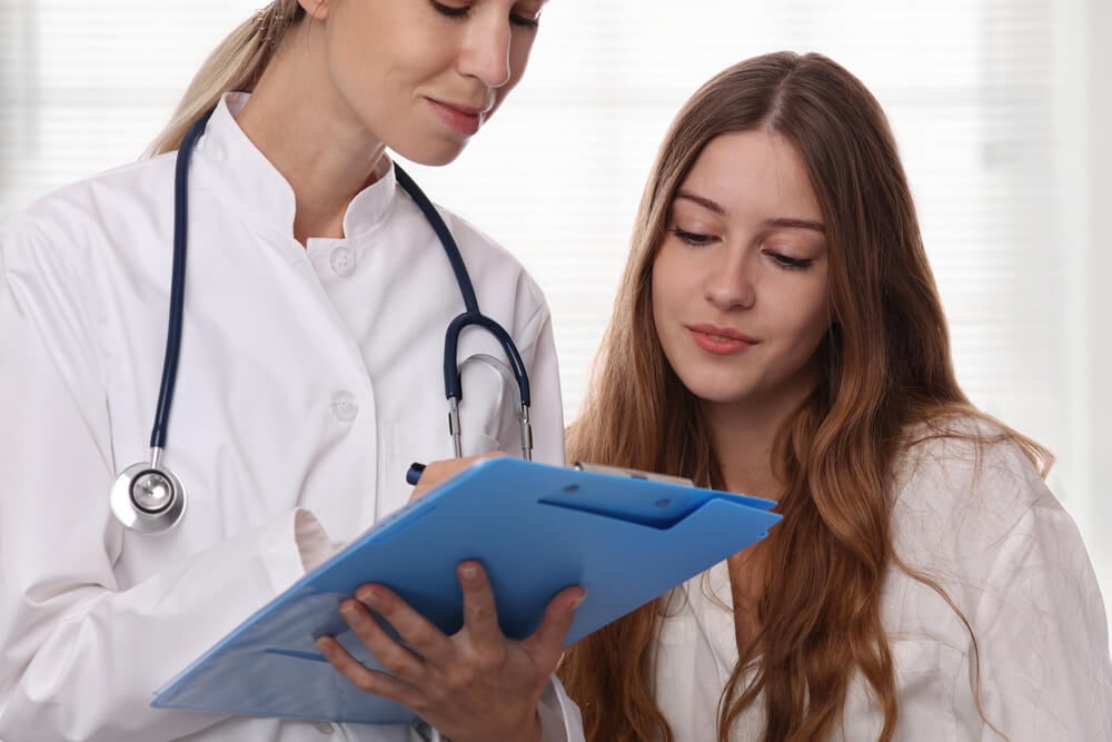 Smiling Female Doctor Showing to Teenage Patient Test Results.