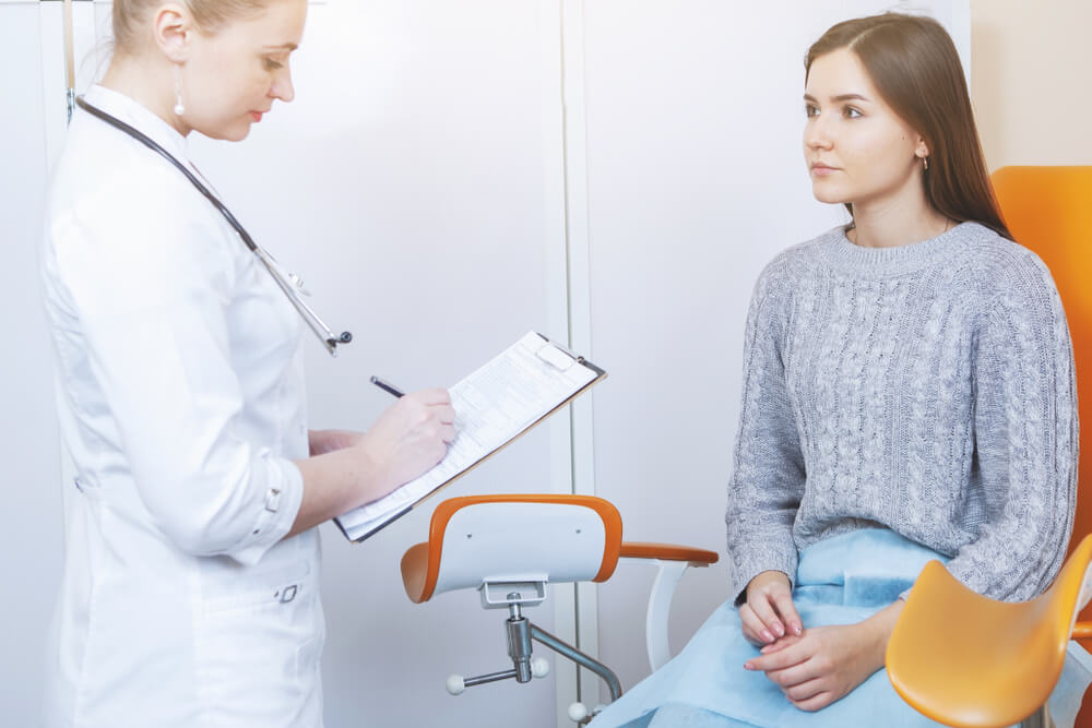 Doctor Gynecologist Talking to a Female Patient in an Orange Chair in a Medical Office.