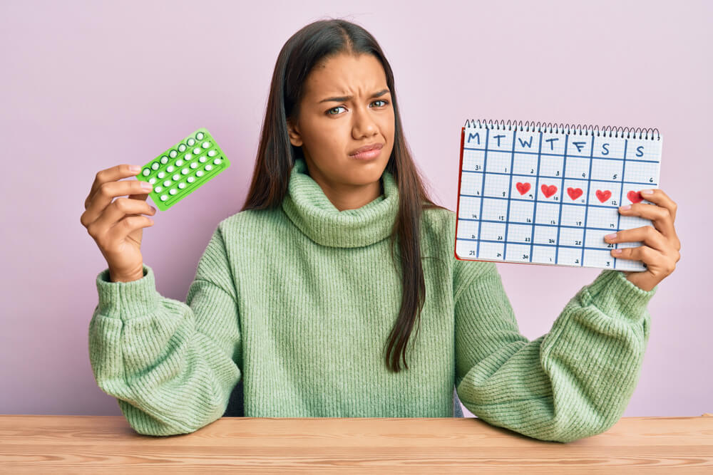 Beautiful Hispanic Woman Holding Birth Control Pills Clueless and Confused Expression.