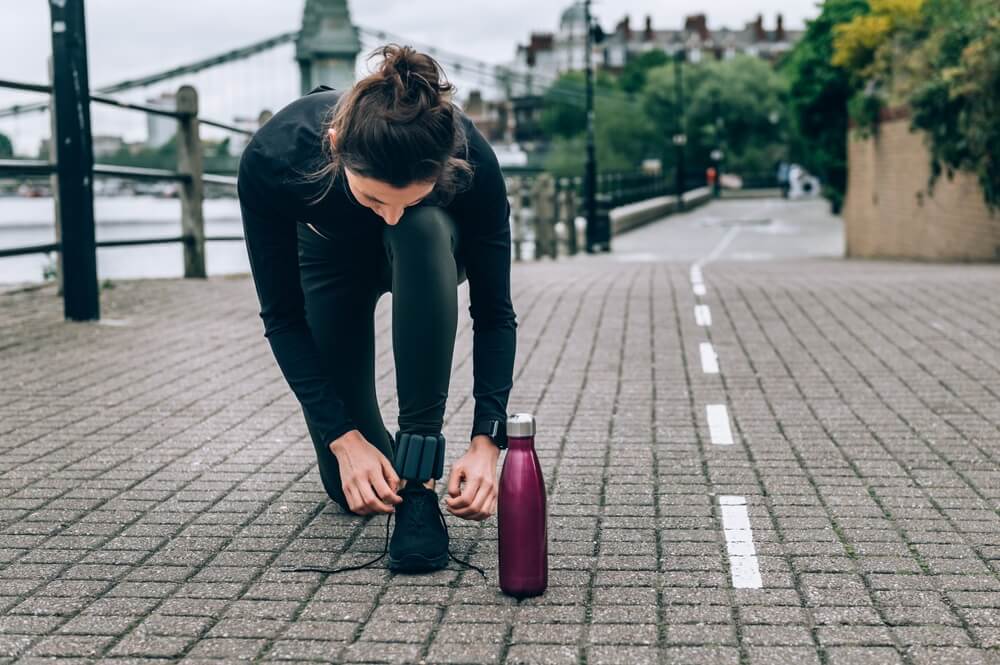 Beautiful Young Slim Woman Is Tying Laces After Jogging Along Embankment of River, London.