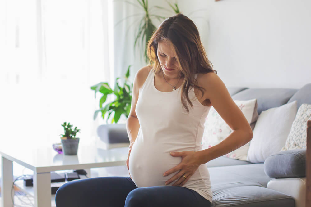 Young Pregnant Woman, Having Painful Contraction, Starting Labor, Sitting on the Couch