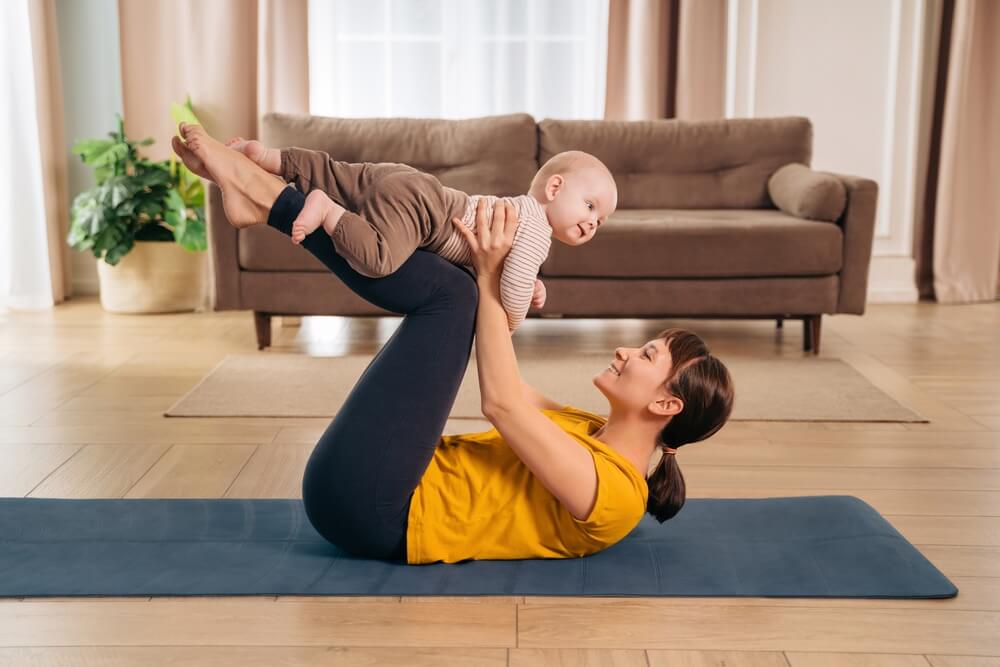 Mom Lifting Her Adorable Little Baby With Her Legs, Doing Post-natal Fitness Exercise