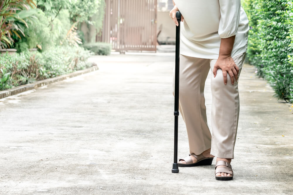 Elderly Woman Standing on the Street She Is Having Symptoms Pain on Both Sides of the Knee, Due to Osteoporosis, to Retirement Age and Health Care Concept.