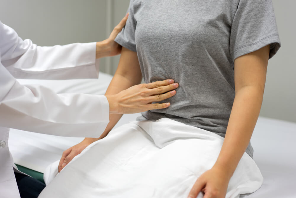 Doctor Examining by Abdominal Palpation of Female Patients Sitting in the Bed Within the Clinic.