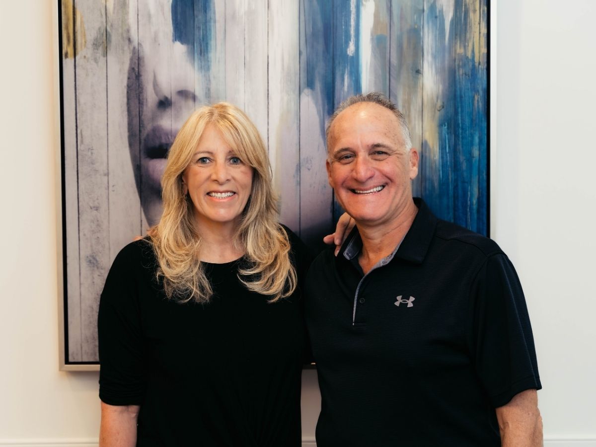Dr. Ellman and Ilona Enlarged photo of Dr. David Ellman & Ilona Blumberg posing together in front of a modern abstract painting
