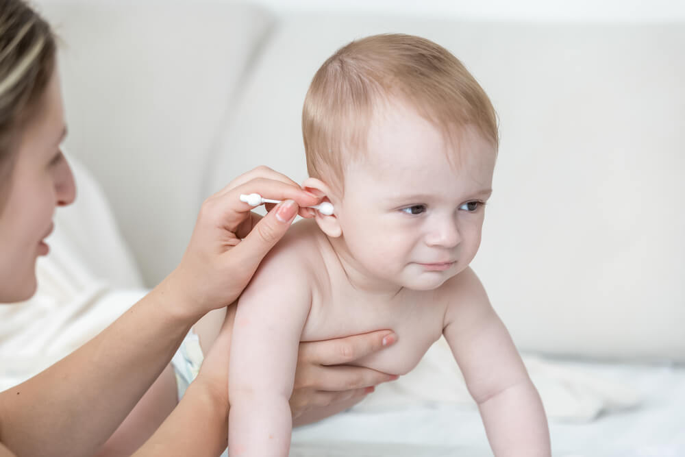 Closeup Photo of Young Mother Cleaning Baby’s Ear With Cotton Swab