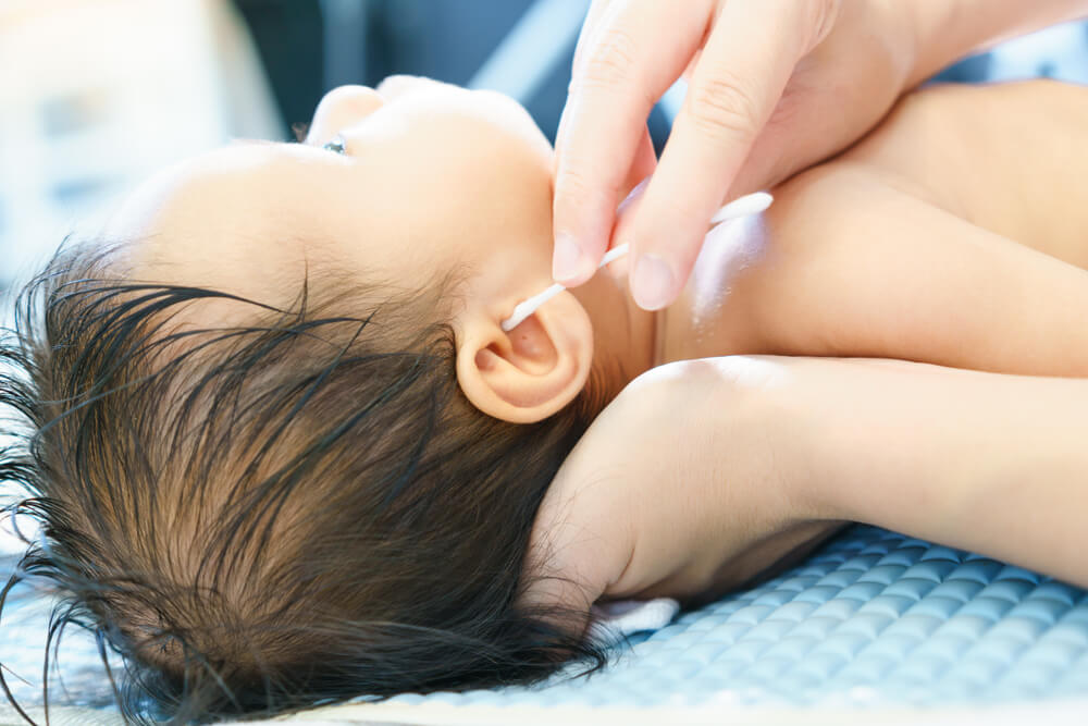 Closeup Photo of Young Mother Cleaning Baby’s Ear With Cotton Swab