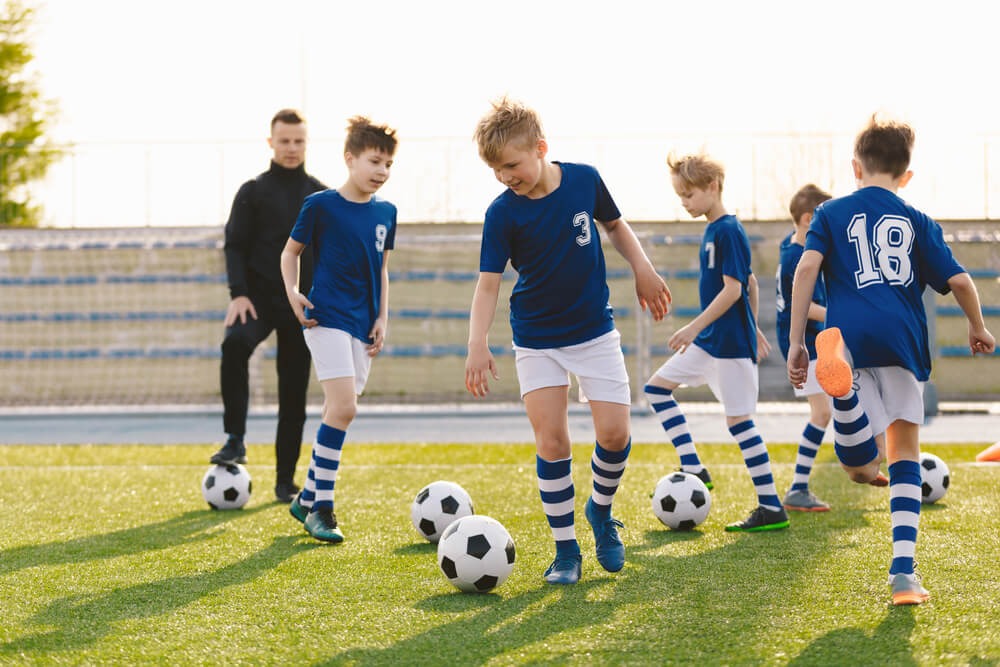 Young Coach With Kids in Soccer Team on Training Unit.