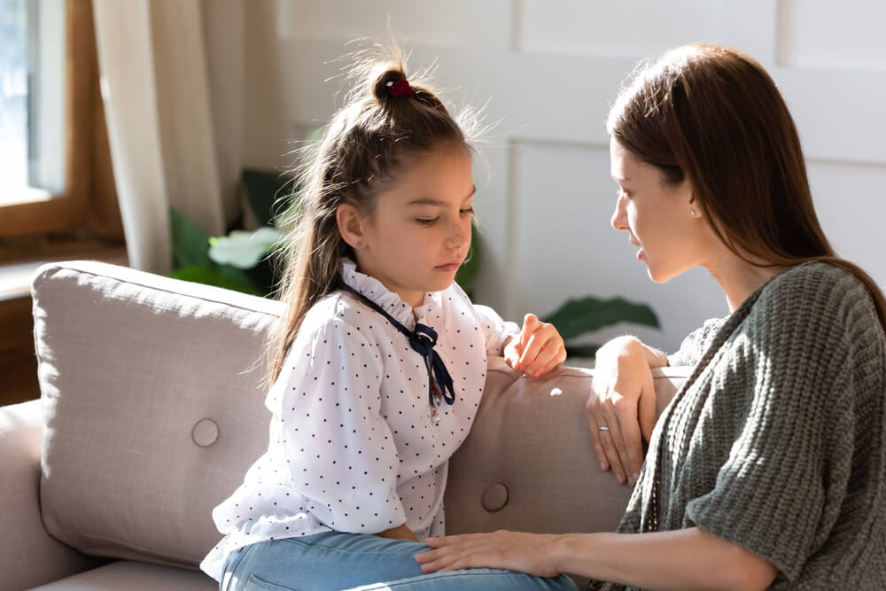 Upset Small Schoolgirl Having Trustful Conversation With Compassionate Young Mother