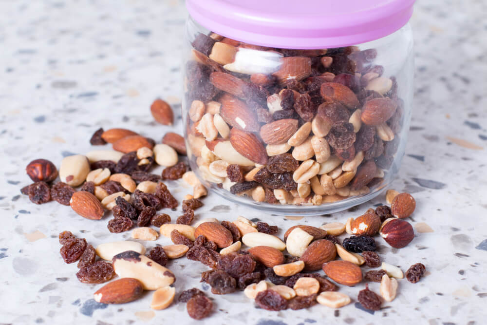 A Mixture of Nuts and Raisins Scattered on a Table From a Glass Jar.