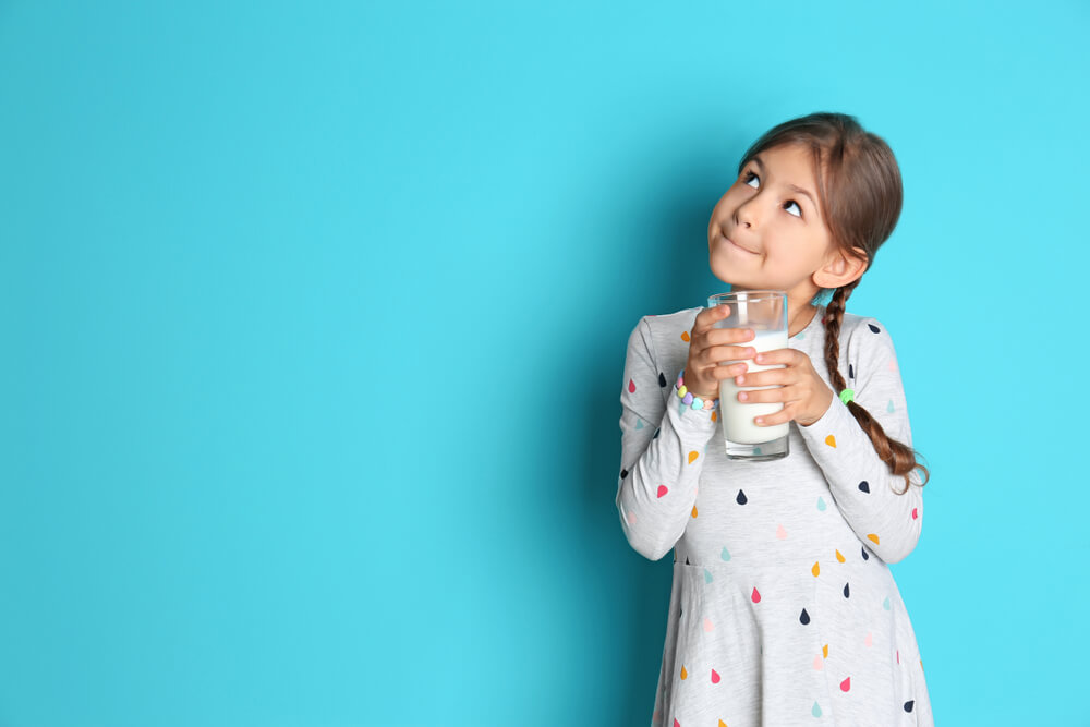 Cute Little Girl With Glass of Milk on Color Background