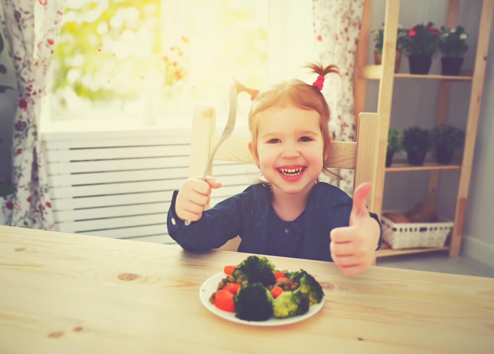 Happy Child Girl Loves to Eat Vegetables and Showing Thumbs Up