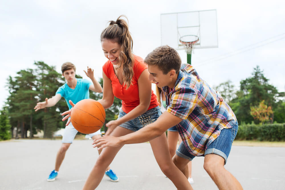 Summer Vacation, Sport, Games and Friendship Concept - Group of Happy Teenagers Playing Basketball Outdoors