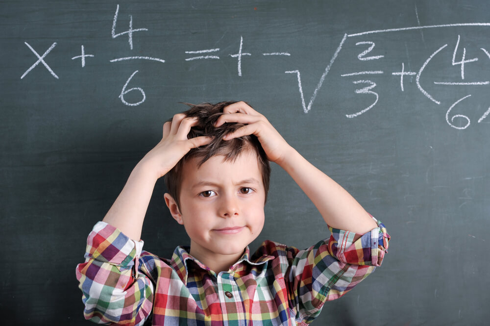 Young Boy in Front of Blackboard With Mathematical Problem Grabbing His Hair