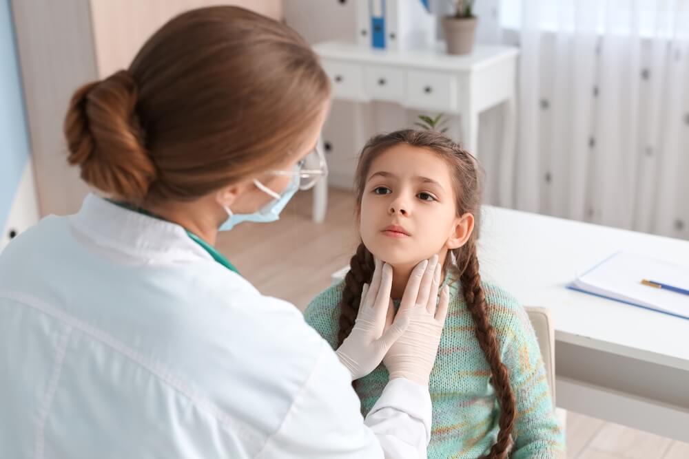 Doctor Examining Little Girl’s Neck in Clinic