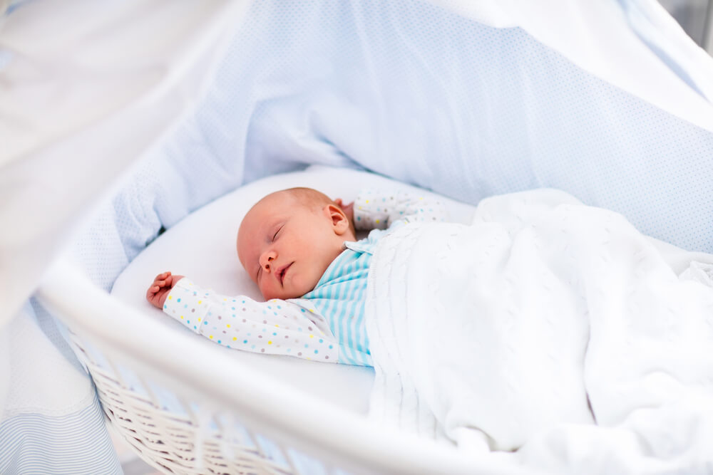 Newborn Baby Boy in Bed. New Born Child Sleeping Under a White Knitted Blanket
