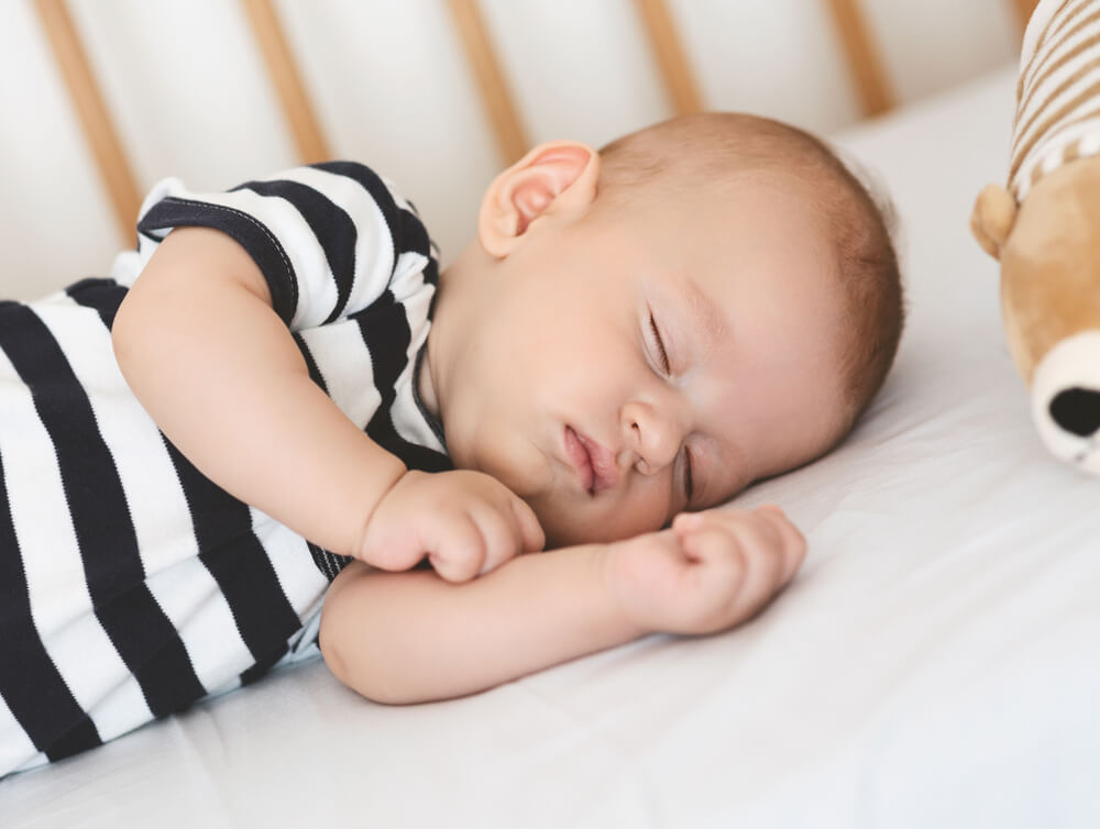 Risk of SIDS Closeup portrait of sleeping newborn baby lying on his side in crib