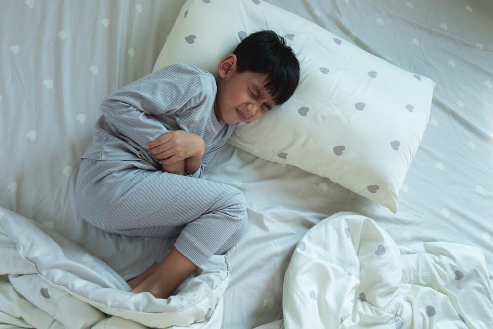 Top View Of Asian Boy Lying In Bed With Stomach Ache Sick Little Child In Bedroom At Home Diarrhea And Illness In Children