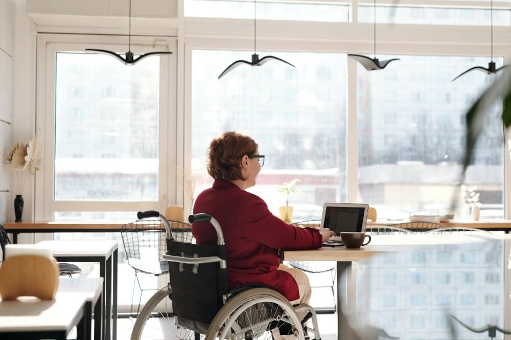 A Woman in in a Wheelchair Working With a Laptop in the Living Room