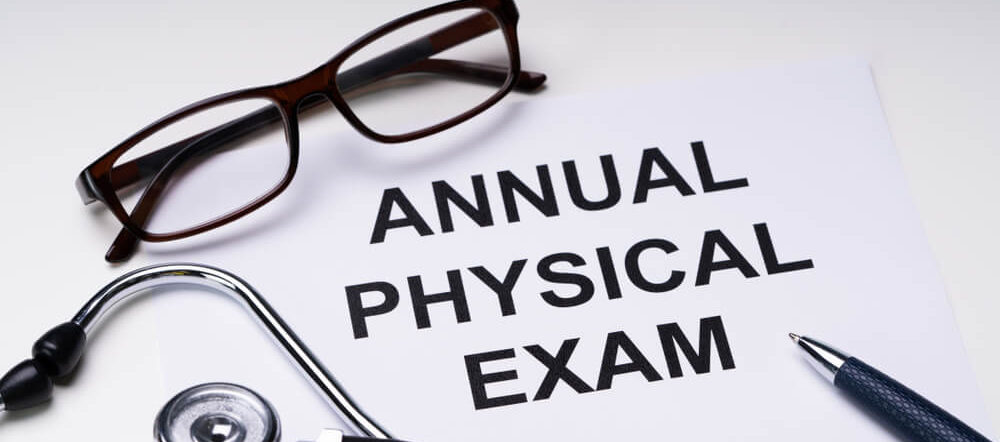 Annual Physical Exam Form With Stethoscope and Spectacles Over White Desk